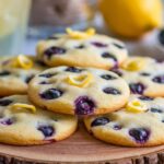 Freshly baked lemon blueberry cookies with blueberries and lemon zest on a plate.